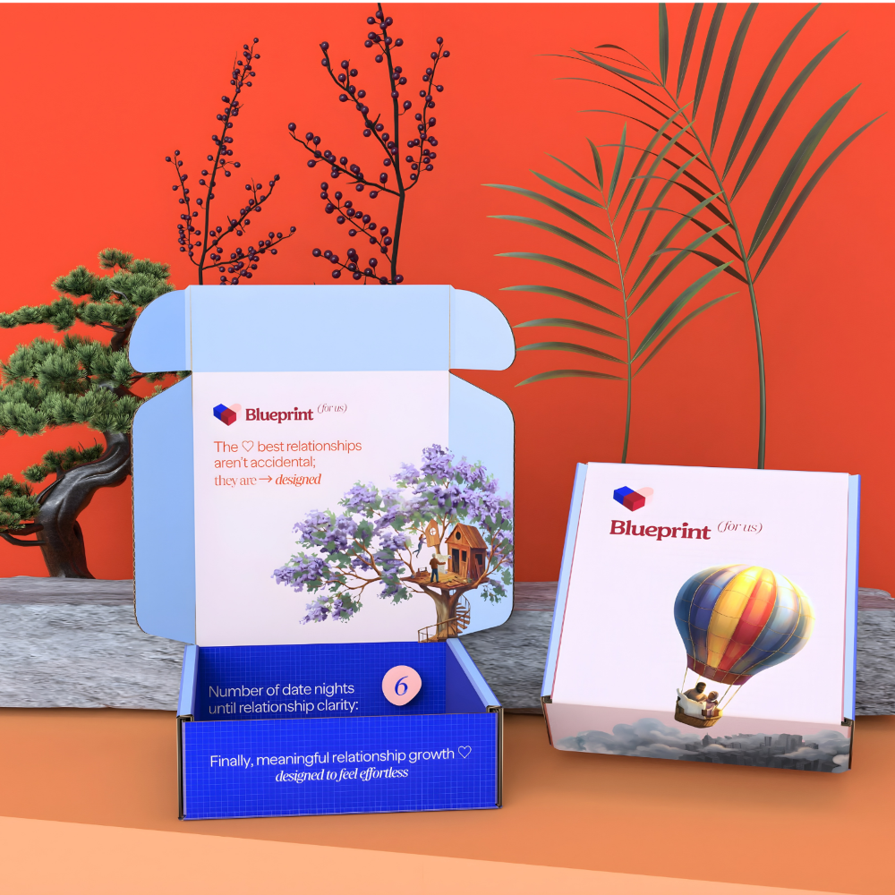 Two 'Blueprint for Love' boxes with decorative elements on a wooden surface and orange background.