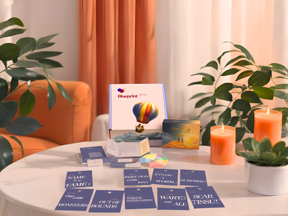 Table with 'Blueprint for us' cards, candles, and plants in a cozy room.