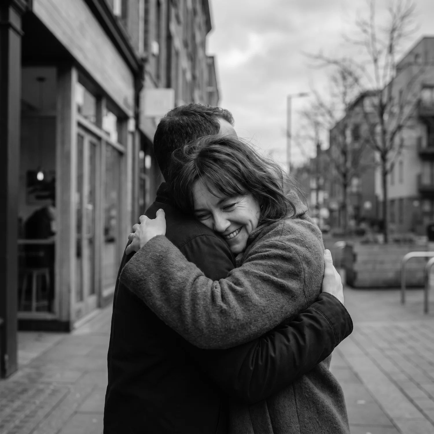 A couple holding each other on a city street, both smiling